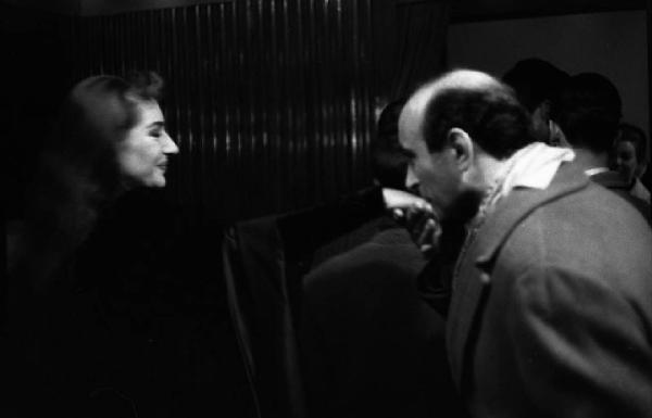 Milano: Teatro alla Scala - Spettacolo Anna Bolena, 1957, regia di Luchino Visconti - Camerino, interno - Uomo bacia la mano a Maria Callas (cantante lirica) - Gruppo di persone sullo sfondo