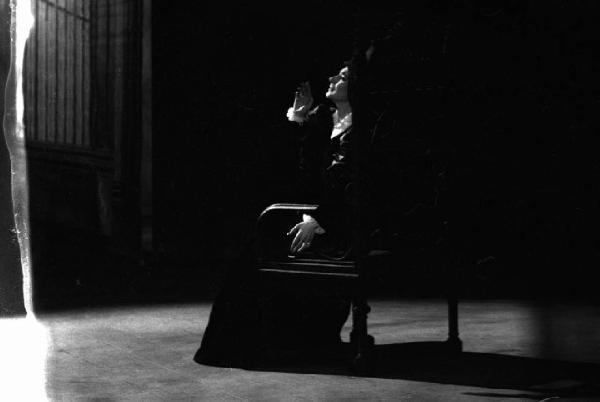 Milano: Teatro alla Scala - Spettacolo Anna Bolena, 1957, regia di Luchino Visconti - Foto di scena - Scenografia - Ritratto femminile: Maria Callas (cantante lirica) seduta su un trono di legno