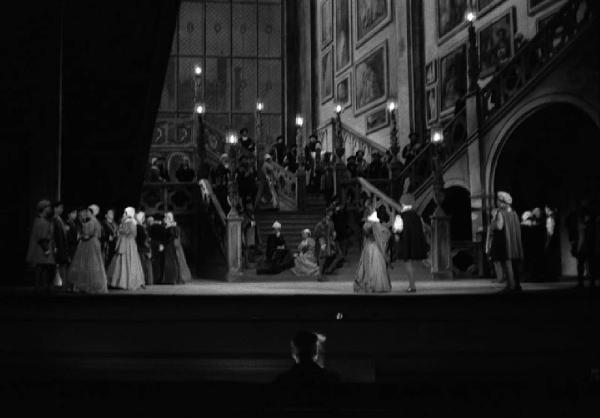 Milano: Teatro alla Scala - Spettacolo Anna Bolena, 1957, regia di Luchino Visconti - Foto di scena - Scenografia - Scalinata - Gruppo di personaggi sul palco - Gianandrea Gavazzeni, direttore d'orchestra di spalle