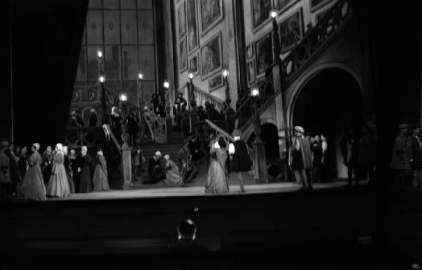 Milano: Teatro alla Scala - Spettacolo Anna Bolena, 1957, regia di Luchino Visconti - Foto di scena - Scenografia - Scalinata - Gruppo di personaggi sul palco - Gianandrea Gavazzeni, direttore d'orchestra di spalle
