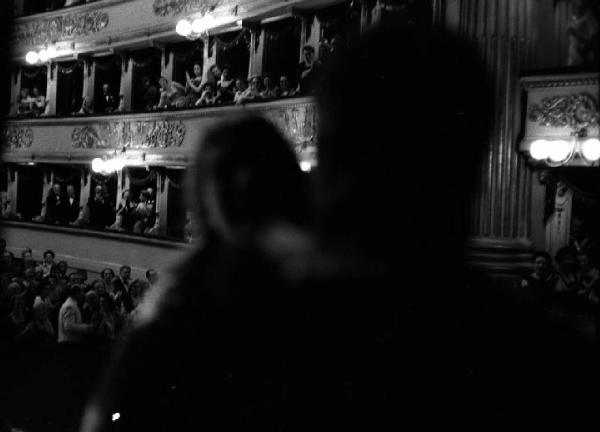 Milano: Teatro alla Scala - Spettacolo Anna Bolena, 1957, regia di Luchino Visconti - Foto di scena - Due personaggi in primo piano - Palchetti e platea con pubblico