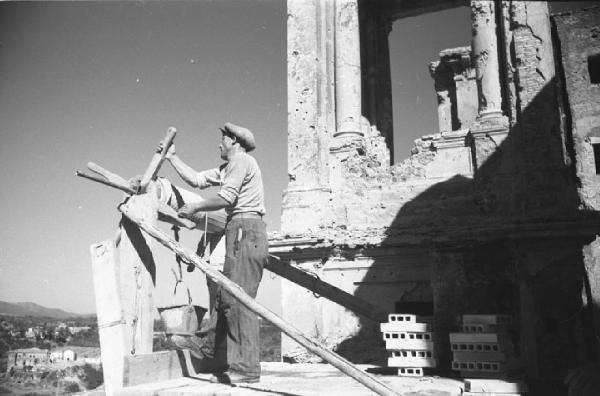 Italia Dopoguerra: Valmontone bombardata. Valmontone - Edificio bombardato - Colonne - Ritratto maschile: uomo tira su un secchio con una carrucola - Cumuli di mattoni