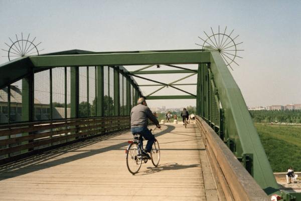 Sesto San Giovanni - Parco Nord, settore Montagnetta - Passerella ciclopedonale Clerici - Persone in bicicletta - Capannone Breda - Campi - Sullo sfondo palazzi di Cinisello Balsamo