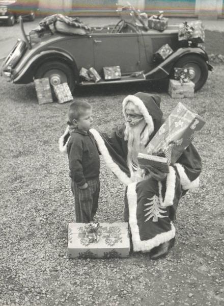 Istituto dei Ciechi di Milano - Cortile davanti all'ingresso - Babbo Natale parla con un bambino - Auto cabriolet carica di regali davanti all'Istituto
