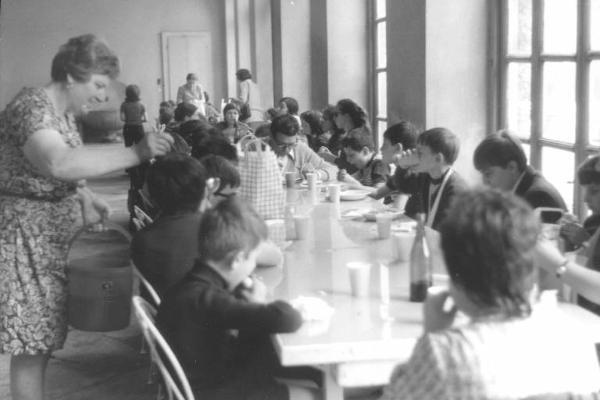 Gita scolastica degli allievi della scuola elementare dell'Istituto dei Ciechi di Milano - Pausa pranzo - Bambini mangiano intorno al tavolo - Donna serve il cibo