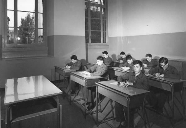 Istituto dei Ciechi di Milano - Scuola avviamento professionale - Interno di aula - Allievi seduti dietro ai banchi scrivono con tavoletta braille