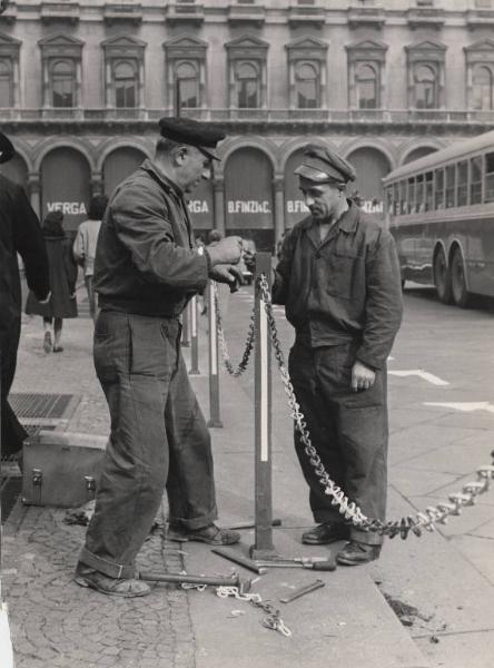 Milano - Piazza del Duomo - Catenelle di fronte al sottopassaggio pedonale per impedire l'accesso ai pedoni - Operai al lavoro