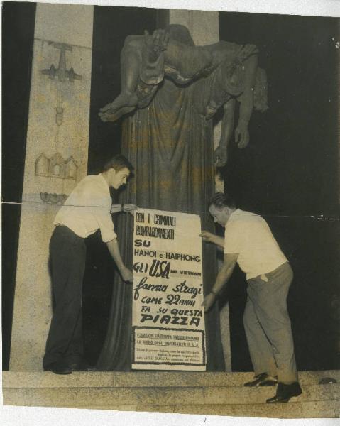 Milano - Via Ponte Vecchio - Monumento " Piccoli Martiri di Gorla" - Due uomini con manifesto contro la guerra in Vietnam