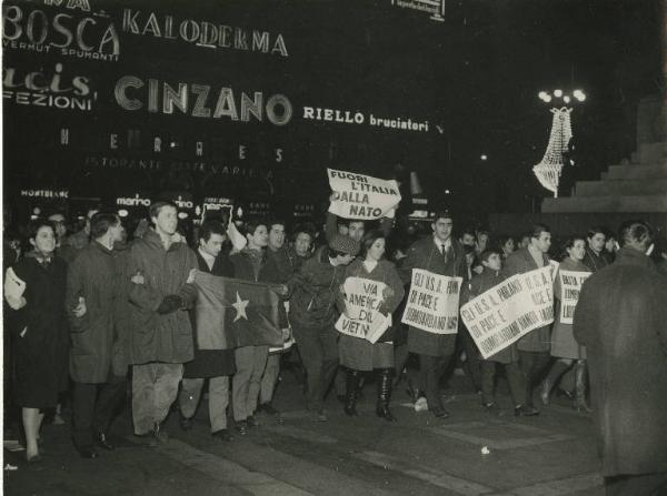 Milano - Manifestazione per il Vietnam - Corteo notturno di giovani recanti cartelli e bandiere - Insegne luminose