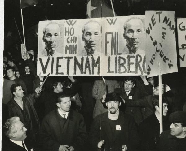 Milano - Manifestazione contro la guerra in Vietnam - Corteo notturno con cartelli di protesta, torce e bandiere - Cartello con il volto Ho Chi Minh