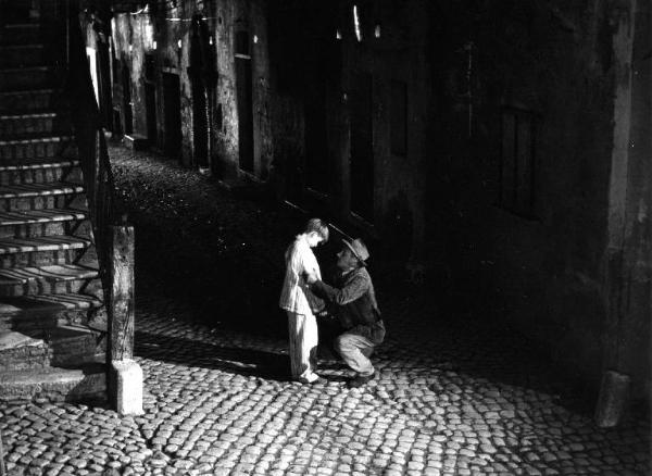 Scena del film "Il padrone sono me" - Regia Franco Brusati - 1955 - L'attore Paolo Stoppa in ginocchio davanti a un bambino in una strada di notte