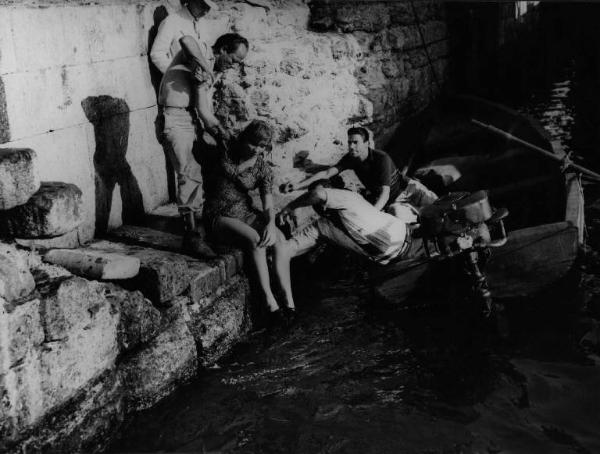 Scena del film "Senza pietà" - Regia Alberto Lattuada - 1948 - L'attrice Carla Del Poggio al bordo di un fiume sorretta da due attori non identificati. Sul motoscafo due attori non identificati