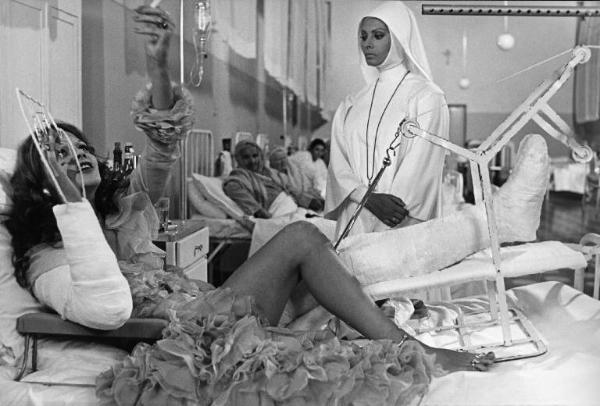 Scena del film "Bianco, rosso e..." - Regia Alberto Lattuada - 1972 - L'attrice Sophia Loren in abito da suora e l'attrice Tina Aumont sul letto di un ospedale