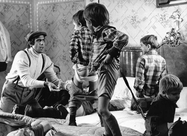 Scena del film "Bianco, rosso e..." - Regia Alberto Lattuada - 1972 - L'attore Adriano Celentano con una siringa e dei bambini sul letto