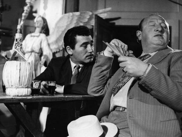 Scena del film "La lupa" - Regia Alberto Lattuada - 1953 - Due attori non identificati al tavolo con una bottiglia di vino