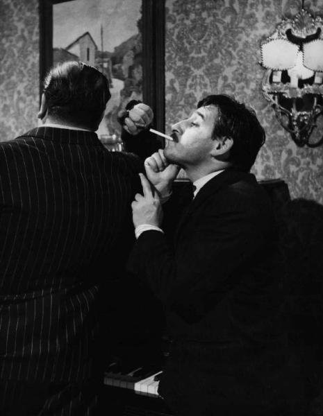 Scena del film "Il cappotto" - Regia Alberto Lattuada - 1952 - L'attore Renato Rascel con una sigaretta e un attore non identificato di spalle