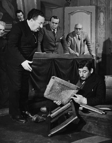 Scena del film "Il cappotto" - Regia Alberto Lattuada - 1952 - L'attore Renato Rascel a terra con una sedia rotta ossrvato dagli attori Ettore G. Mattia, Mimmo Poli e tre attori non identificati