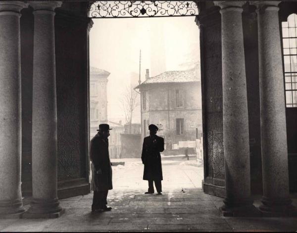 Scena del film "Il cappotto" - Regia Alberto Lattuada - 1952 - L'attore Renato Rascel davanti a un portone con un attore non identificato