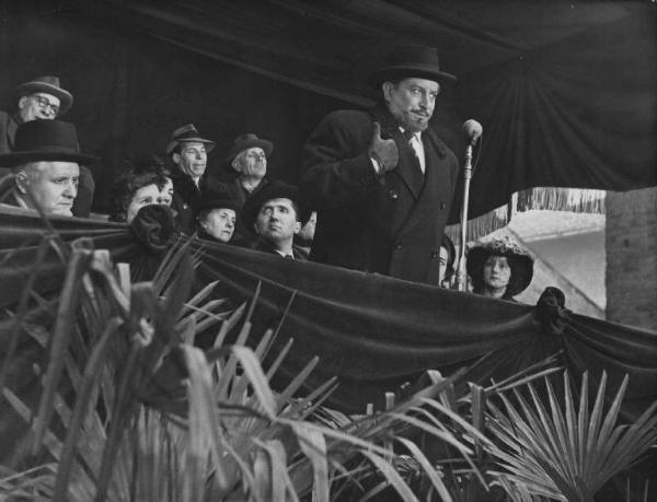 Scena del film "Il cappotto" - Regia Alberto Lattuada - 1952 - L'attore Giulio Stival al microfono su un palco. Dietro di lui un gruppo di attori non identificati