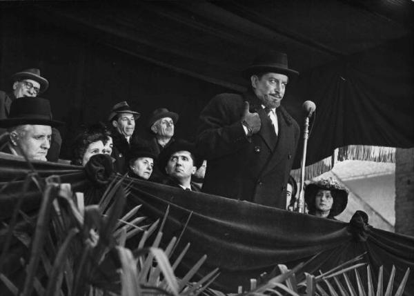 Scena del film "Il cappotto" - Regia Alberto Lattuada - 1952 - L'attore Giulio Stival al microfono su un palco. Dietro di lui un gruppo di attori non identificati