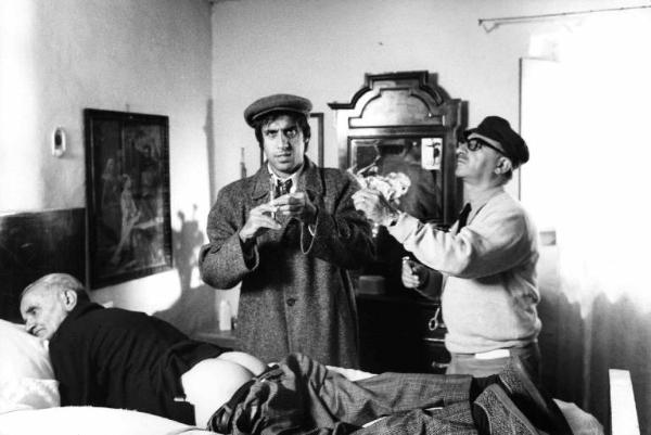 Set del film "Bianco, rosso e..." - Regia Alberto Lattuada - 1972 - Il regista Alberto Lattuada e l'attore Adriano Celentano che prepara un iniezione per un attore non identificato