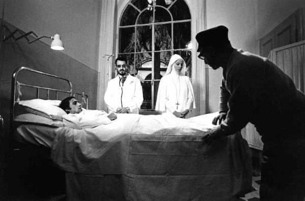 Set del film "Bianco, rosso e..." - Regia Alberto Lattuada - 1972 - Il regista Alberto Lattuada sul set con gli attori Adriano Celentano, a letto in ospedale, e Sophia Loren, in abito da suora, e un attore non identificato