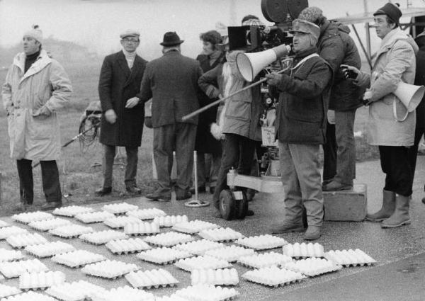 Set del film "Bianco, rosso e..." - Regia Alberto Lattuada - 1972 - Il regista Alberto Lattuada col megafono sul set dietro la macchina da presa con degli operatori su una strada piena di uova