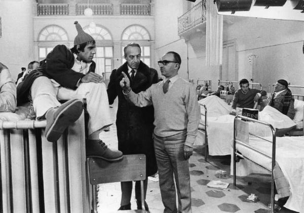 Set del film "Bianco, rosso e..." - Regia Alberto Lattuada - 1972 - Il regista Alberto Lattuada sul set con l'attore Adriano Celentano in ospedale