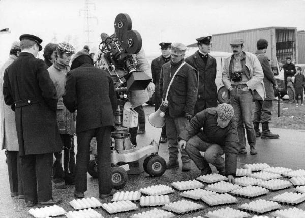 Set del film "Bianco, rosso e..." - Regia Alberto Lattuada - 1972 - Il regista Alberto Lattuada col megafono sul set dietro la macchina da presa con degli operatori su una strada piena di uova