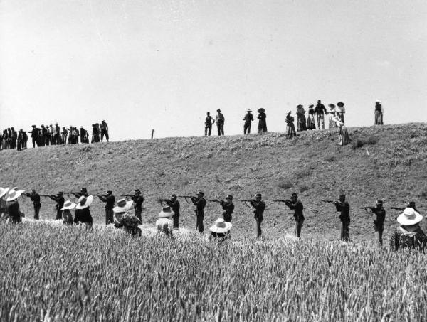 Scena del film "Il mulino del Po" - Regia Alberto Lattuada - 1948 - Fila di uomini in divisa con fucili spianati e gruppi di contadini