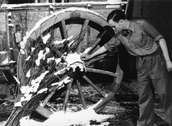 Scena del film "Giacomo l'idealista" - Regia Alberto Lattuada - 1943 - Un operatore sul set accanto a una ruota di un carro