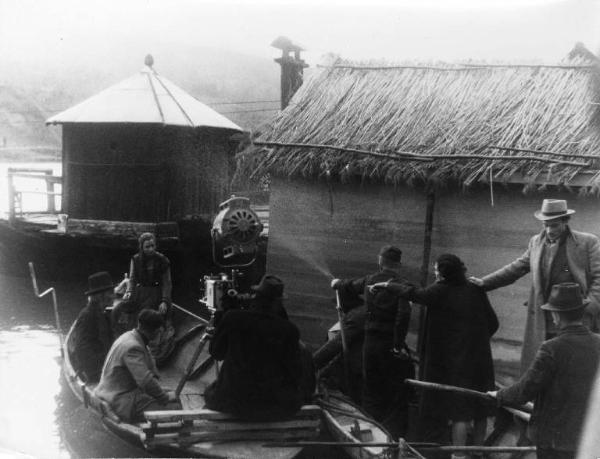 Set del film "Giacomo l'idealista" - Regia Alberto Lattuada - 1943 - Gli attori Massimo Serato e Marina Berti in barca con due attori non identificati. Il regista Alberto Lattuada dietro la macchina da presa con alcuni operatori