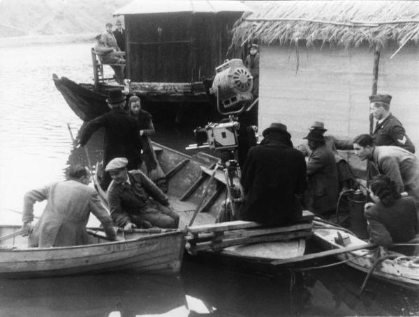 Set del film "Giacomo l'idealista" - Regia Alberto Lattuada - 1943 - L'attrice Marina Berti e un attore non identificato su una barca . Attorno il regista Alberto Lattuada e gli operatori della troupe