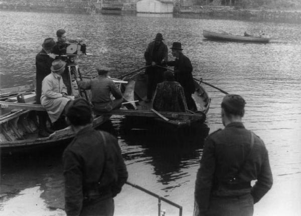 Set del film "Giacomo l'idealista" - Regia Alberto Lattuada - 1943 - Il regista Alberto Lattuata con alcuni operatori dietro la macchina da presa e l'attrice Marina Berti con due attori non identificati su una barca.