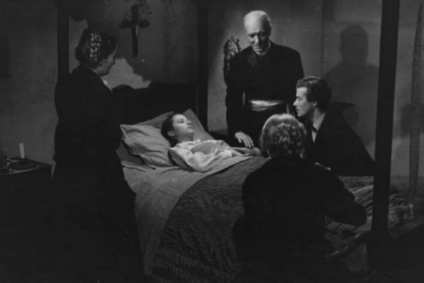 Scena del film "Giacomo l'idealista" - Regia Alberto Lattuada - 1943 - Gli attori Massimo Serato e Marina Berti, a letto, un prete e due attrici non identificate