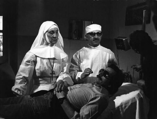 Set del film "Oh! Serafina" - Regia Alberto Lattuada - 1976 - Il regista Alberto Lattuda vestito da infermiere con attori non identificati nella sala operatoria