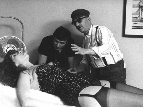 Set del film "Oh! Serafina" - Regia Alberto Lattuada - 1976 - Il regista Alberto Lattuada e un operatore con l'attrice Angelica Ippolito stesa su un lettino