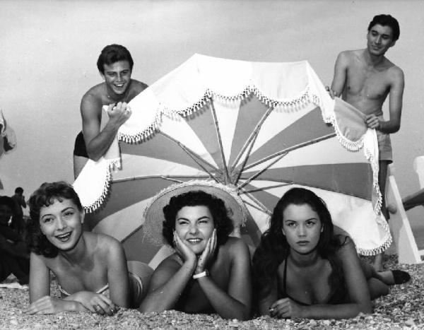 Scena del film "La spiaggia" - Regia Alberto Lattuada - 1953 - L'attrice Valeria Moriconi e quattro attori non identificati sotto l'ombrellone