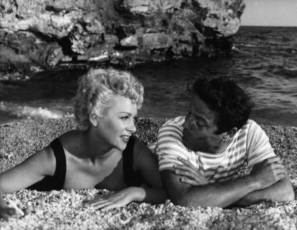 Scena del film "La spiaggia" - Regia Alberto Lattuada - 1953 - Gli attori Martine Carol e Raf Vallone sulla spiaggia in riva al mare