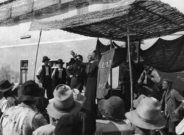 Scena del film "Il mulino del Po" - Regia Alberto Lattuada - 1948 - Gli attori Nino Pavese, Pina Gallini, Giulio Cali su un palco e una folla di attori non identificati