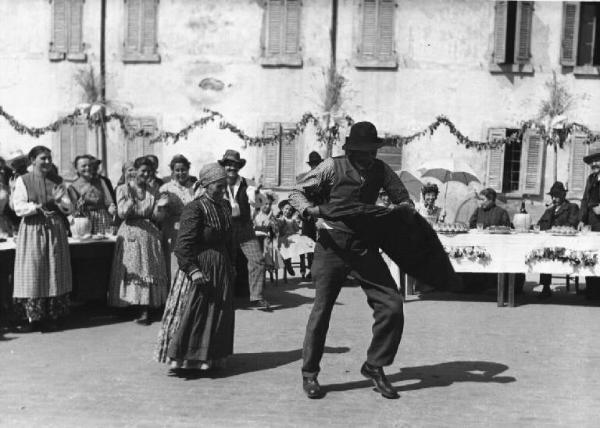 Scena del film "Il mulino del Po" - Regia Alberto Lattuada - 1948 - Un gruppo di contadini in piazza per una festa di paese. Sullo sfondo l'attrice Anna Carena