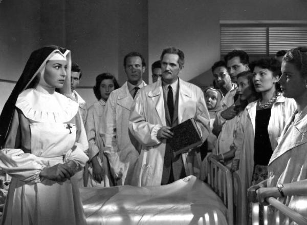 Scena del film "Anna" - Regia Alberto Lattuada - 1951 - L'attrice Silvana Mangano, in veste di suora infermiera, con gli attori Jacques Dumesnil, Piero Lulli, in camice bianco e vari infermieri in ospedale