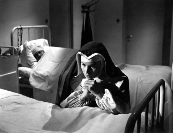 Scena del film "Anna" - Regia Alberto Lattuada - 1951 - L'attrice Silvana Mangano in abito da suora infermiera prega inginocchiata a un letto in ospedale