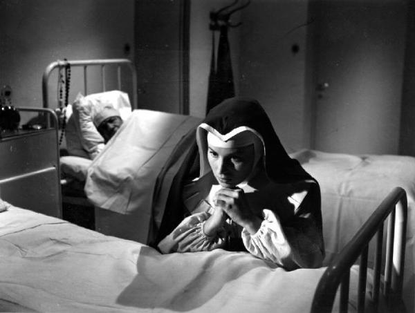 Scena del film "Anna" - Regia Alberto Lattuada - 1951 - L'attrice Silvana Mangano in abito da suora infermiera prega inginocchiata a un letto in ospedale