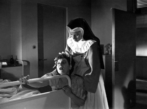 Scena del film "Anna" - Regia Alberto Lattuada - 1951 - Le attrici Dina Perbellini, aggrappata al letto, e Silvana Mangno, in abito da suora infermiera, in ospedale