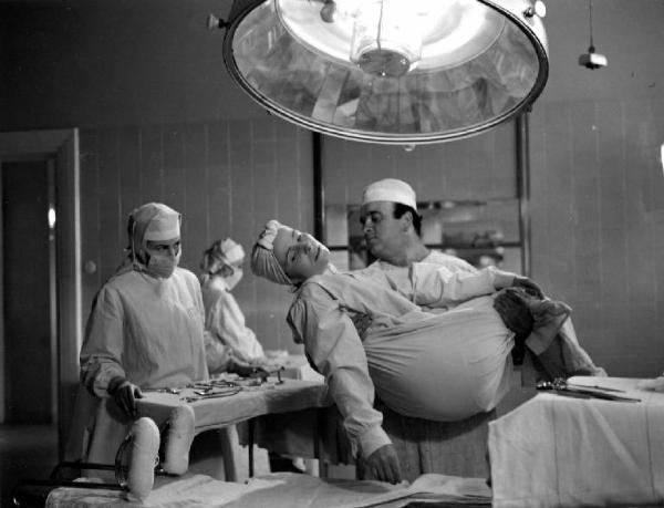 Scena del film "Anna" - Regia Alberto Lattuada - 1951 - L'attore Mimmo Poli infermiere sorregge una paziente
