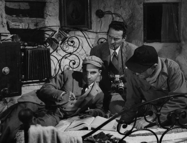 Set del film "La lupa" - Regia Alberto Lattuada - 1953 - Il regista Alberto Lattuada sul set con il fotografo Federico Patellani e un operatore della troupe su un letto