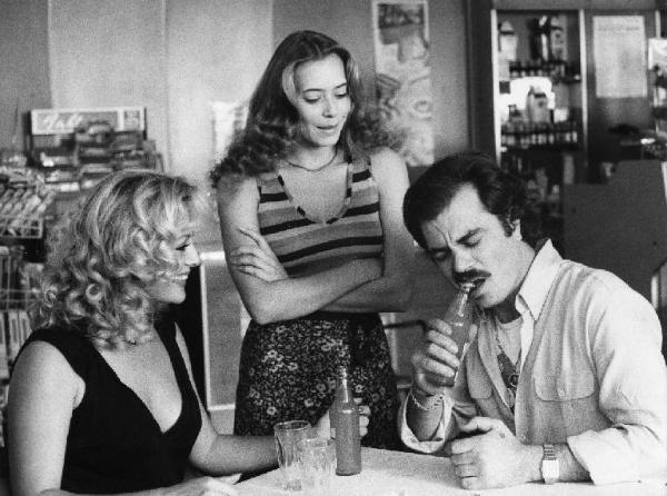 Scena del film "La cicala" - Regia Alberto Lattuada - 1980 - Le attrici Virna Lisi e Barbara De Rossi osservano l'attore Antonio Catanfora stappare una bottiglia con i denti in un bar