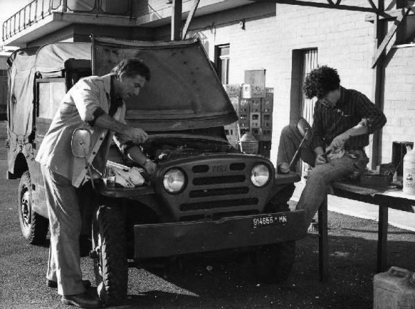 Scena del film "La cicala" - Regia Alberto Lattuada - 1980 - L'attore Anthony Franciosa e un attore non identificato riparano un'automobile