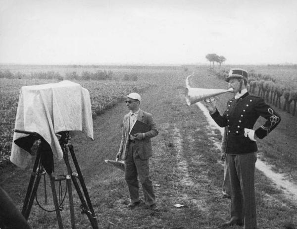 Set del film "Il mulino del Po" - Regia Alberto Lattuada - 1948 - Il regista Alberto Lattuada dietro la macchina da presa e un attore in divisa con un megafono sul set